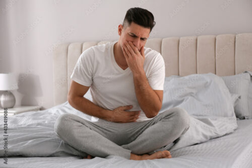 man with food poisoning feeling sick on bed