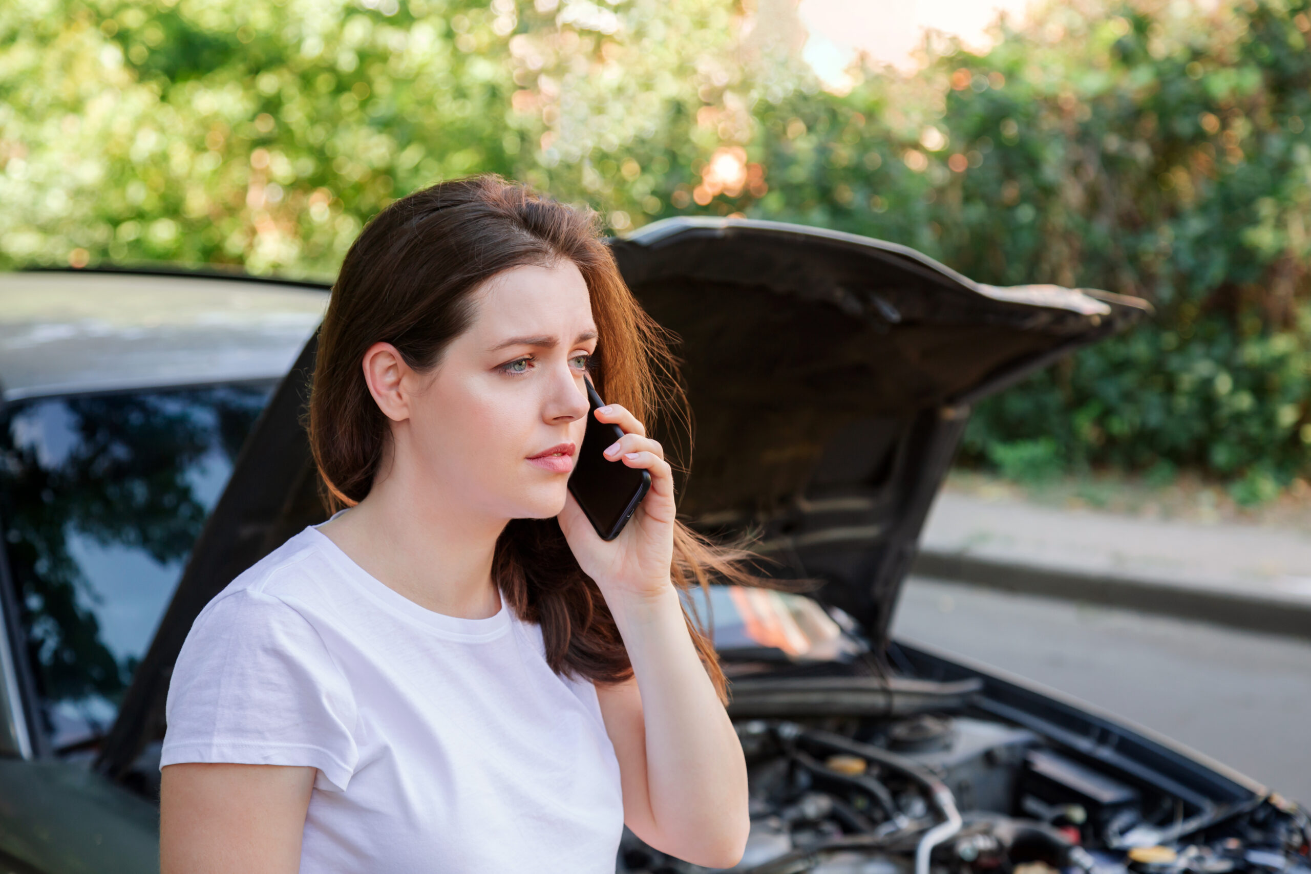 woman on phone in front of car