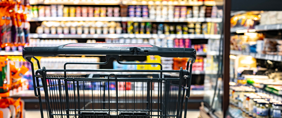 A shopping cart by a store shelf in a supermarket