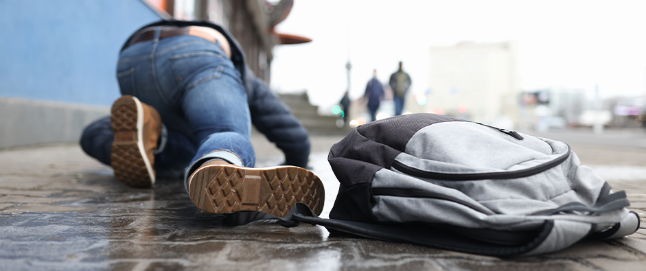 Man with backpack lying on slippery sidewalk after fall closeup
