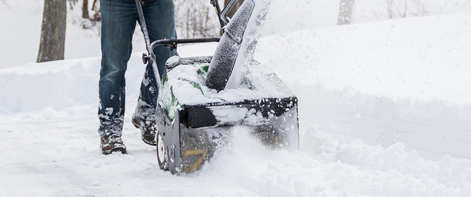 Snow blower in action clearing a residential driveway after snow storm