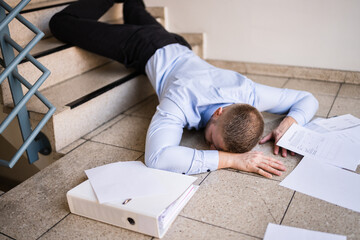 man and papers at the bottom of the stairs after falling