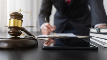 person writing on desk with gavel