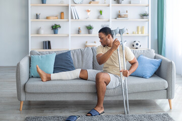 man with broken leg and crutches on couch