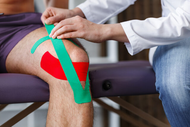 man's knee in physical therapy tape